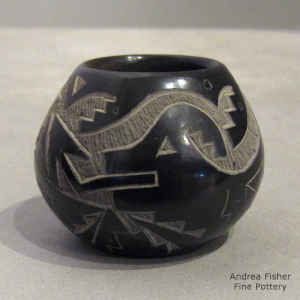A sgraffito hummingbird, avanyu and geometric design on a miniature black jar with sienna spots