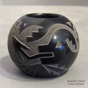A sgraffito avanyu, kokopelli and geometric design on a miniature black seed pot with a sienna spot