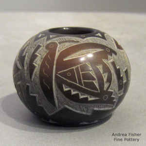 A sgraffito hummingbird, butterfly and geometric design on a miniature black seed pot with sienna spots