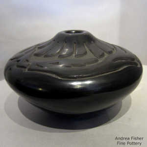 Feather and avanyu design carved into a black seed pot
