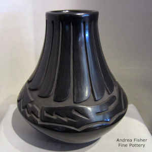 An avanyu and feather design carved into a black jar