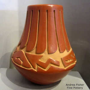 Avanyu and feather design carved into a red jar