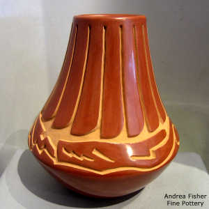 Feather and avanyu design carved into a tall red jar