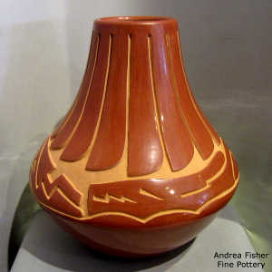 Feather and avanyu design carved into a tall red jar