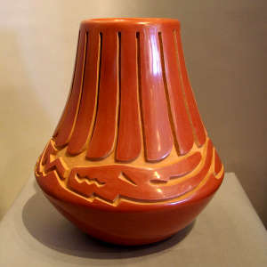 Feather and avanyu design carved into a tall red jar