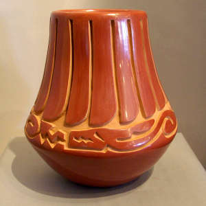 Feather and avanyu design carved into a tall red jar