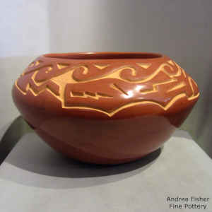 An avanyu and geometric design carved into a red jar