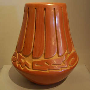 Feather and avanyu design carved into a polished red jar