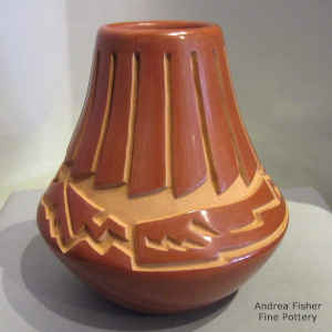 An avanyu design carved into a red jar