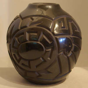 Bird and geometric designs carved into a polished black jar