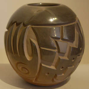 Hand, bear, kiva step and geometric design carved into a polished brown jar