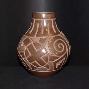 Spiral, turtle and geometric design carved into a brown on brown jar