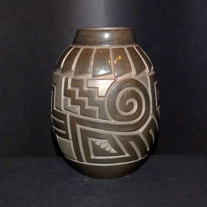 Feathers, bear paw, spiral and cross design carved in a brown on brown jar