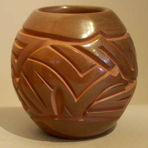 Stylized bear and geometric design carved into a brown jar