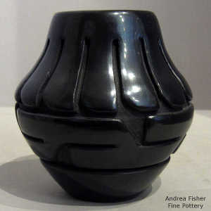 Feather and geometric design carved into a polished black jar