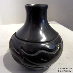 An avanyu and geometric design carved into a black jar