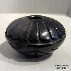 Feather and geometric design carved into a polished black jar