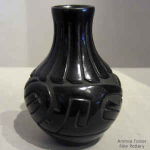 An avanyu and feather design carved into a black water jar