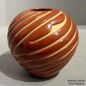 Swirl design carved into a polished red jar