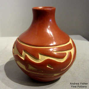 An avanyu design carved into a polished red jar