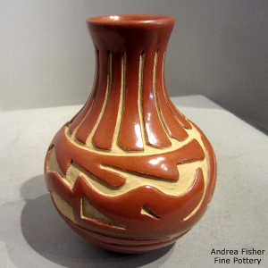 Avanyu and geometric design carved into a polished red jar