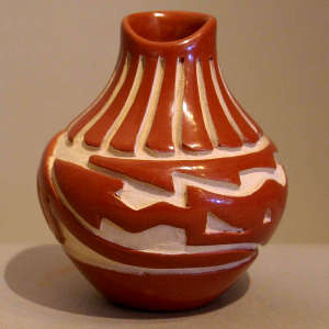 Feather and avanyu design carved into a polished red jar