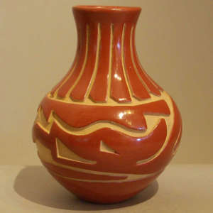 Feather and avanyu design carved into a polished red jar