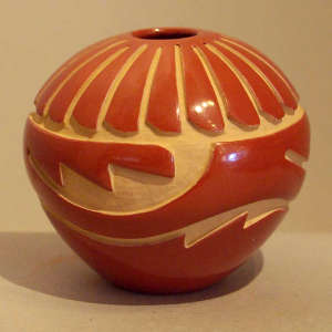 Feather and geometric design carved into a polished red jar