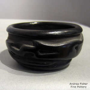 An avanyu design carved into a black jar