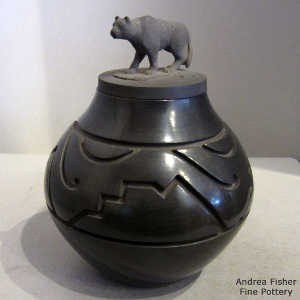 Geometric design carved into a black jar with a mountain lion figure on the lid
