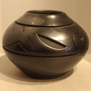Stylized avanyu and geometric design carved into a black jar
