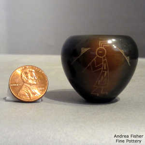 Sgraffito dancers and kokopelli in sienna spots on a miniature black jar