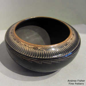 Sgraffito avanyu, bear paw, feather and geometric design on a black bowl with a sienna rim