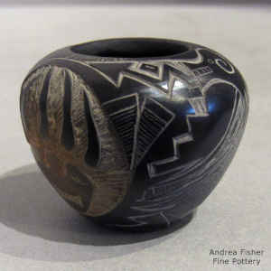 A sgraffito avanyu, pueblo, bear paw and geometric design on a miniature black jar
