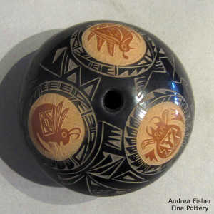 Geometric design and sgraffito rabbit, bird and crab medallions on a black seed pot with sienna spots