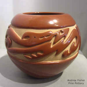 An avanyu and geometric design carved into a red jar
