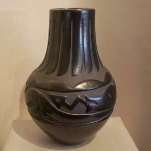 Avanyu and feather design carved into a black jar