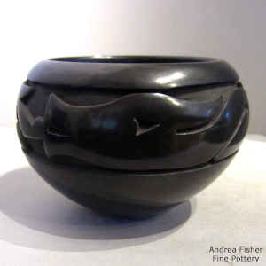 An avanyu design carved into a black jar