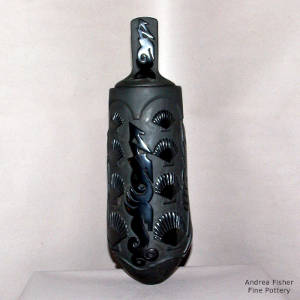 Avanyu and sea shell designs carved into a lidded black jar