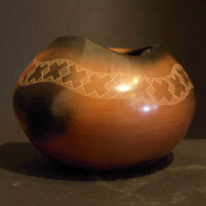 Band of sgraffito geometric designs on a red jar with fire clouds and an organic opening