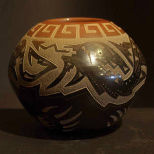 Sgraffito avanyu, key and bear paw designs on a black jar with a sienna rim