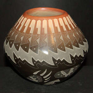 Sgraffito bear paw, feahter and geometric design on a black jar with a sienna rim