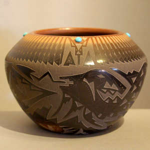 Sgraffito avanyu design and inlaid stones on a black jar with sienna rim