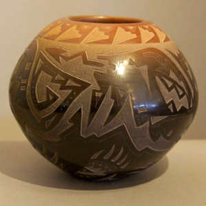 Sgraffito avanyu, bear paws and geometric design on a black jar with a sienna rim