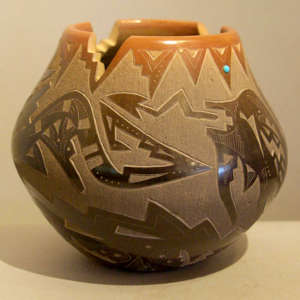 Sgraffito avanyu and geometric design on a black jar with a cut sienna rim and inlaid stone