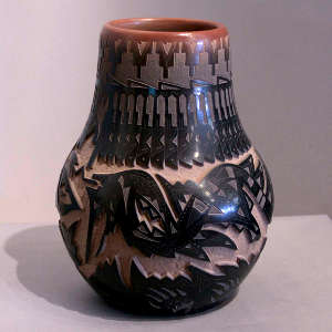 Sgraffito bear paw, feather, avanyu and geometric design on a black jar with a sienna rim