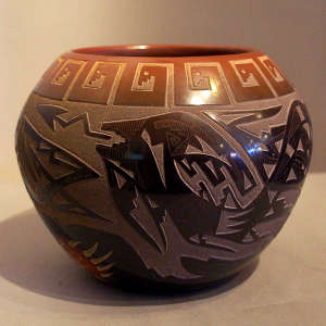 Sgraffito avanyu, bear paw and geometric design on a black jar with a sienna rim