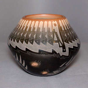 Sgraffito bear paw, feather and geometric design on a black jar with a sienna rim