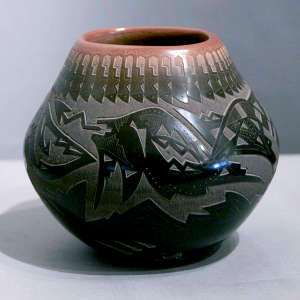 Sgraffito avanyu, bear paw and geometric design on a black jar with a sienna rim