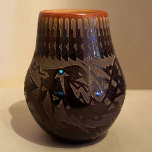 Sgraffito avanyu, feather and geometric design on a black jar with a sienna rim